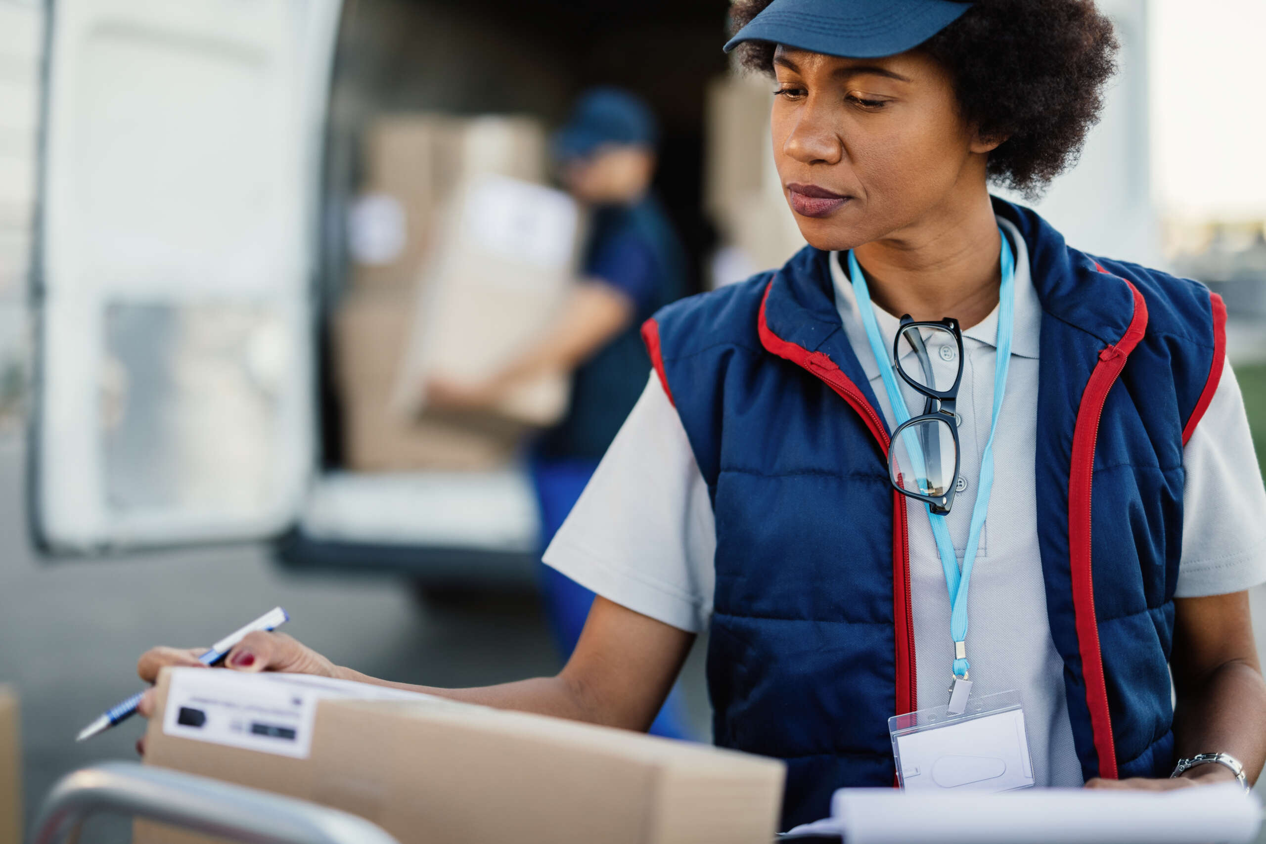 Black female deliverer checking package data before the shipment